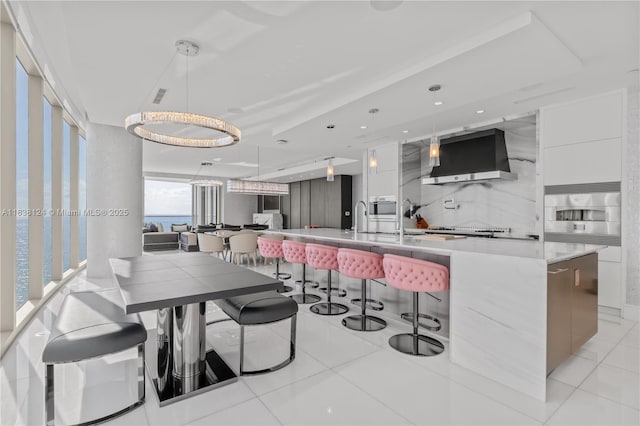 17975 Collins Ave Unit 1202, Sunny Isles Beach, FL 33160 - kitchen featuring modern cabinets, wall chimney range hood, white cabinetry, a spacious island, and recessed lighting