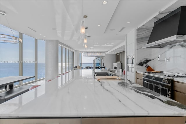 17975 Collins Ave Unit 1202, Sunny Isles Beach, FL 33160 - kitchen with wall chimney range hood, a large island with sink, modern cabinets, open floor plan, and recessed lighting