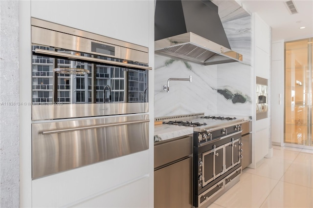 17975 Collins Ave Unit 1202, Sunny Isles Beach, FL 33160 - kitchen with extractor fan, a warming drawer, stainless steel appliances, backsplash, and light tile patterned floors
