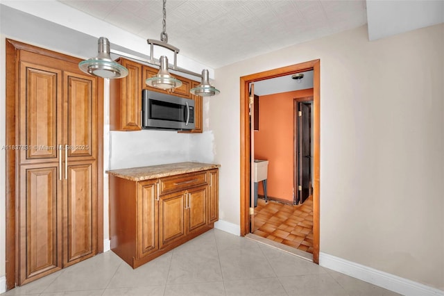 911 Mockingbird Ln, Plantation, FL 33324 - kitchen with stainless steel microwave, brown cabinetry, light stone countertops, and an ornate ceiling