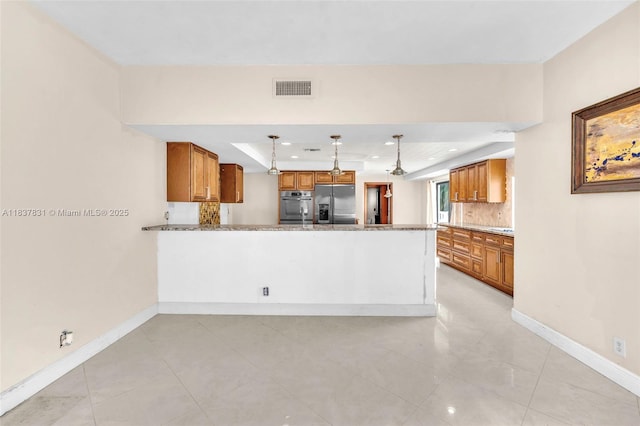 911 Mockingbird Ln, Plantation, FL 33324 - kitchen featuring stainless steel appliances, a raised ceiling, brown cabinets, backsplash, and a peninsula
