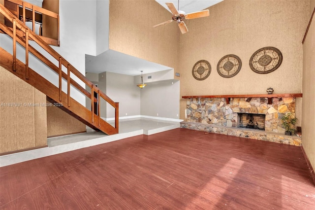 911 Mockingbird Ln, Plantation, FL 33324 - unfurnished living room featuring a towering ceiling, wood finished floors, stairway, ceiling fan, and a stone fireplace