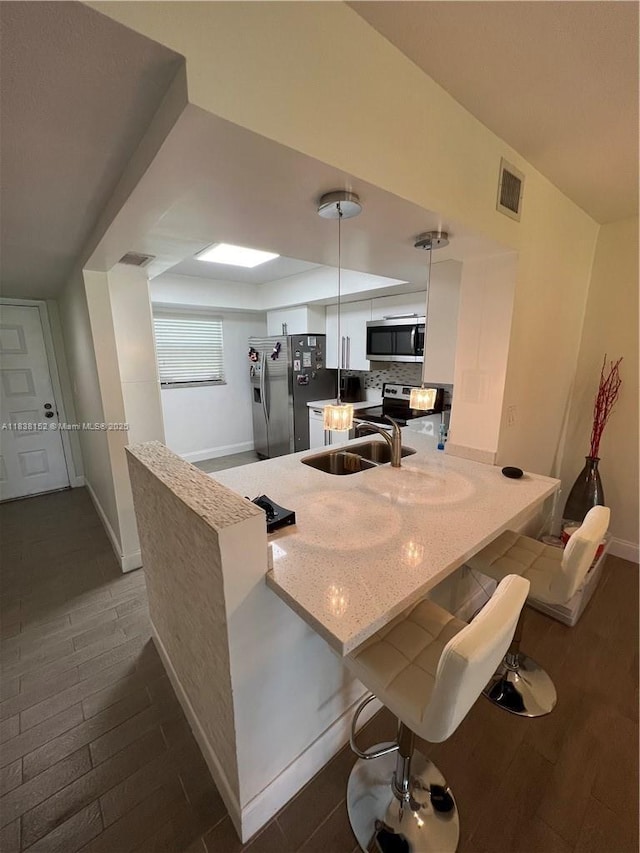 16171 Blatt Blvd Unit 104, Weston, FL 33326 - kitchen featuring appliances with stainless steel finishes, a peninsula, white cabinetry, a kitchen bar, and dark wood-style floors