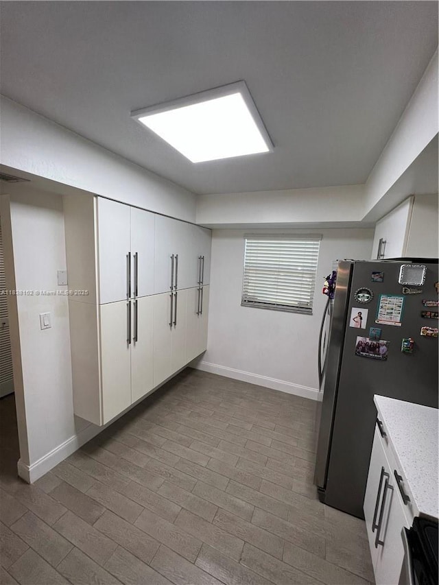 16171 Blatt Blvd Unit 104, Weston, FL 33326 - kitchen with freestanding refrigerator, white cabinetry, wood finished floors, light stone countertops, and electric range oven