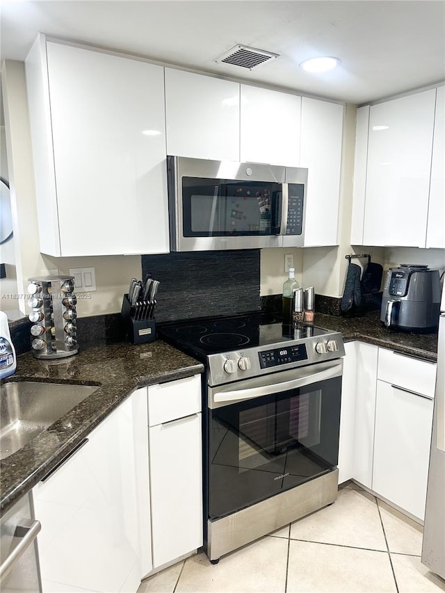 2351 Douglas Rd Unit 702, Miami, FL 33145 - kitchen featuring stainless steel appliances, white cabinets, dark stone countertops, and modern cabinets