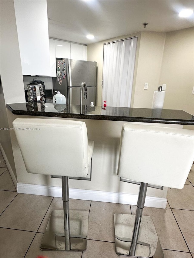 2351 Douglas Rd Unit 702, Miami, FL 33145 - kitchen with freestanding refrigerator, white cabinetry, tile patterned floors, and dark countertops