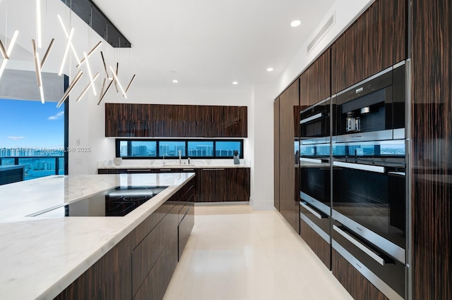 18555 Collins Ave Unit 2003, Sunny Isles Beach, FL 33160 - kitchen featuring modern cabinets, dark brown cabinets, black electric cooktop, light stone countertops, and recessed lighting