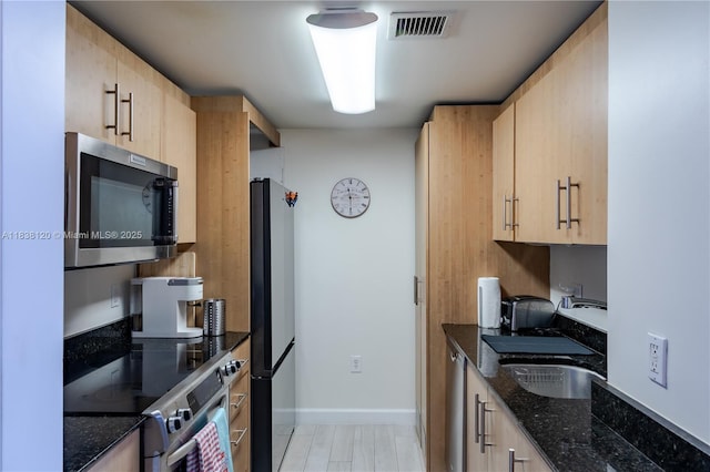 10275 Collins Ave Unit 634, Bal Harbour, FL 33154 - kitchen with appliances with stainless steel finishes, light brown cabinetry, and dark stone countertops