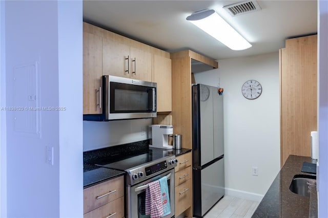 10275 Collins Ave Unit 634, Bal Harbour, FL 33154 - kitchen with stainless steel appliances, light brown cabinetry, dark stone counters, and light wood-style floors