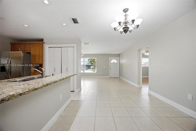 9540 NW 25th St, Sunrise, FL 33322 - kitchen with stainless steel refrigerator with ice dispenser, a chandelier, light stone countertops, brown cabinetry, and light tile patterned floors