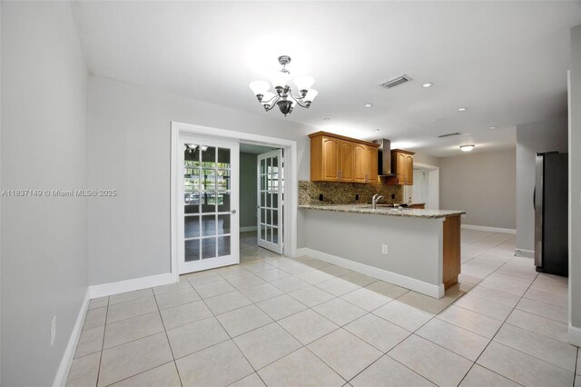 9540 NW 25th St, Sunrise, FL 33322 - kitchen with a chandelier, freestanding refrigerator, a peninsula, tasteful backsplash, and light stone countertops
