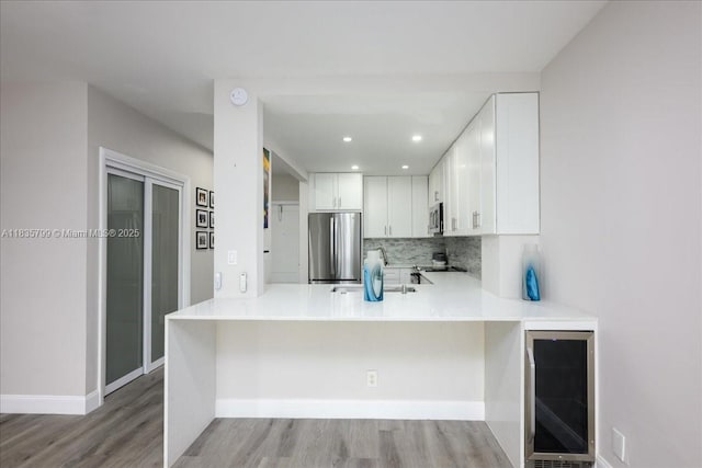 1200 SW 12th St Unit 214, Fort Lauderdale, FL 33315 - kitchen with beverage cooler, stainless steel appliances, backsplash, light wood-style floors, and a peninsula