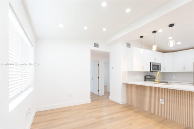 1896 NW 66th St, Miami, FL 33147 - kitchen with stainless steel microwave, light countertops, light wood finished floors, a peninsula, and recessed lighting