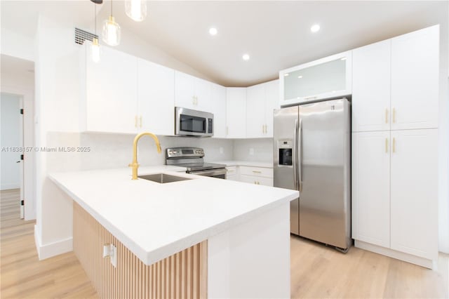 1896 NW 66th St, Miami, FL 33147 - kitchen with appliances with stainless steel finishes, light wood-style flooring, a peninsula, light countertops, and glass insert cabinets