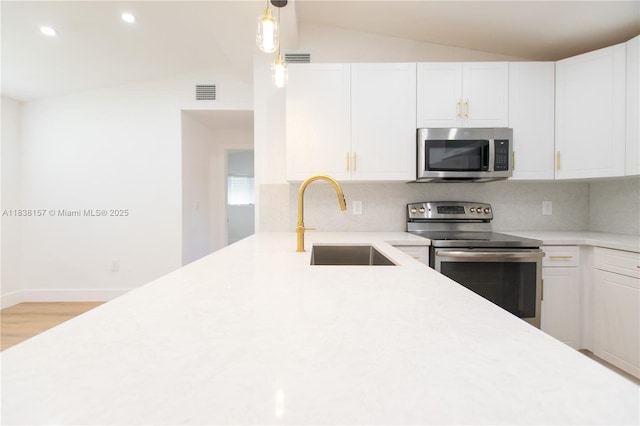 1896 NW 66th St, Miami, FL 33147 - kitchen featuring appliances with stainless steel finishes, vaulted ceiling, tasteful backsplash, light countertops, and white cabinets