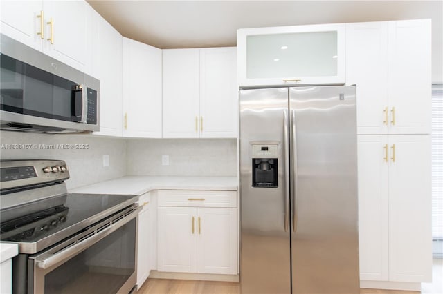 1896 NW 66th St, Miami, FL 33147 - kitchen featuring appliances with stainless steel finishes, light countertops, white cabinets, and backsplash