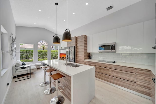 15281 Wilshire Ct, Pembroke Pines, FL 33027 - kitchen with appliances with stainless steel finishes, modern cabinets, a breakfast bar, light countertops, and decorative backsplash