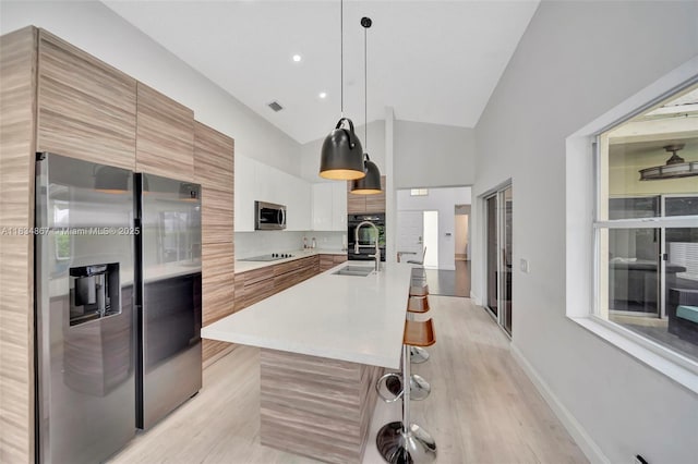 15281 Wilshire Ct, Pembroke Pines, FL 33027 - kitchen featuring black appliances, modern cabinets, light countertops, light wood-style floors, and hanging light fixtures