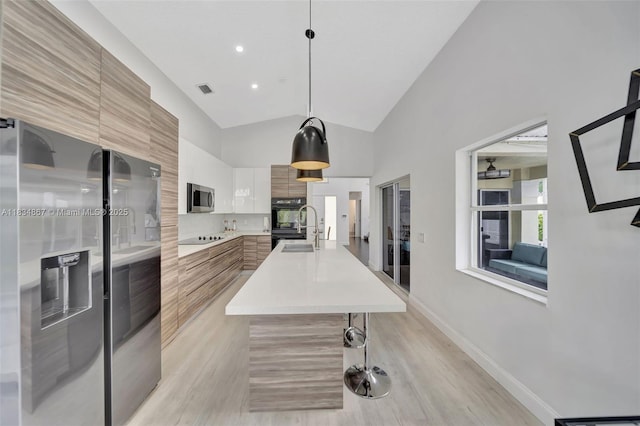 15281 Wilshire Ct, Pembroke Pines, FL 33027 - kitchen with modern cabinets, black appliances, light countertops, light wood-style flooring, and a spacious island