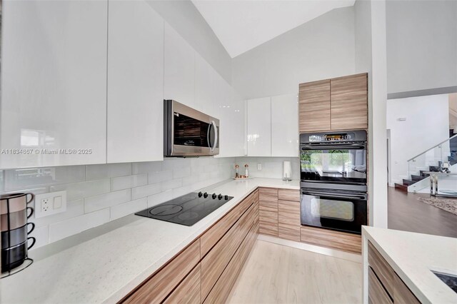 15281 Wilshire Ct, Pembroke Pines, FL 33027 - kitchen featuring black appliances, modern cabinets, high vaulted ceiling, white cabinets, and backsplash
