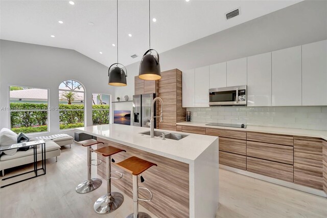 15281 Wilshire Ct, Pembroke Pines, FL 33027 - kitchen featuring stainless steel appliances, modern cabinets, decorative backsplash, vaulted ceiling, and a breakfast bar
