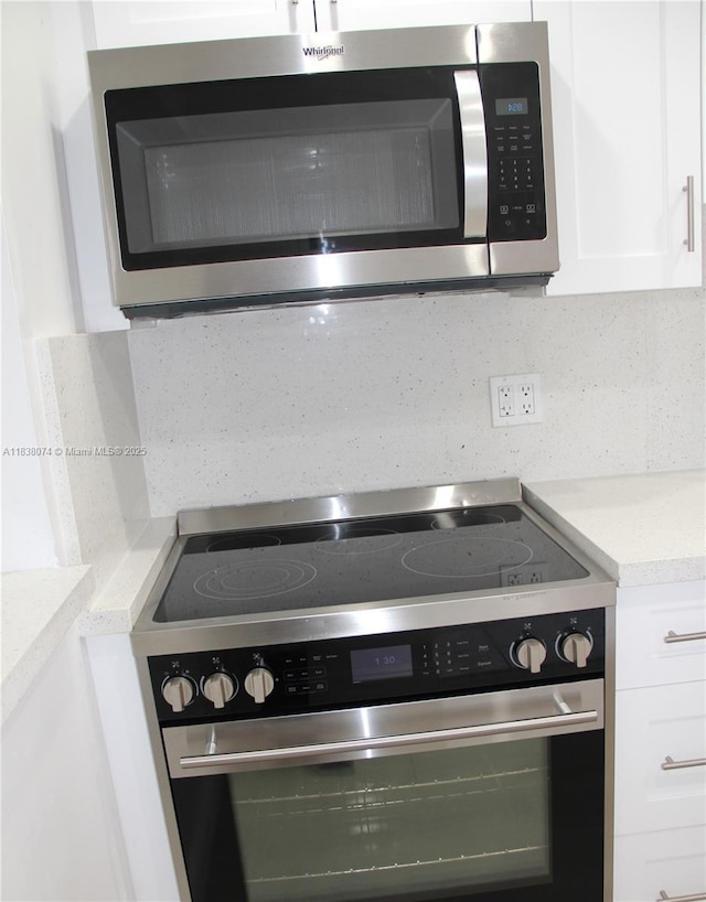 1075 W 68th St Unit 110, Hialeah, FL 33014 - kitchen view of stainless steel appliances, white cabinetry, light countertops, and decorative backsplash