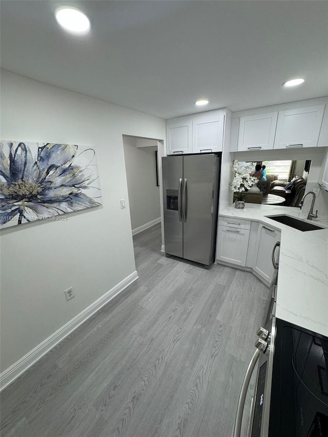 7480 NW 17th St Unit 103, Plantation, FL 33313 - kitchen with stainless steel appliances, light wood finished floors, white cabinetry, recessed lighting, and light stone countertops