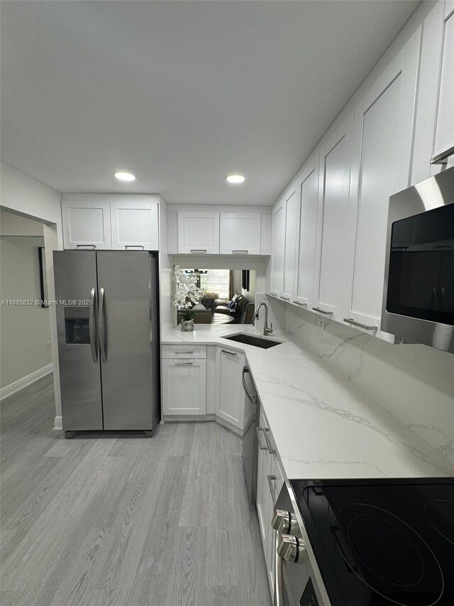 7480 NW 17th St Unit 103, Plantation, FL 33313 - kitchen featuring stainless steel appliances, white cabinets, light wood-style flooring, recessed lighting, and light stone countertops