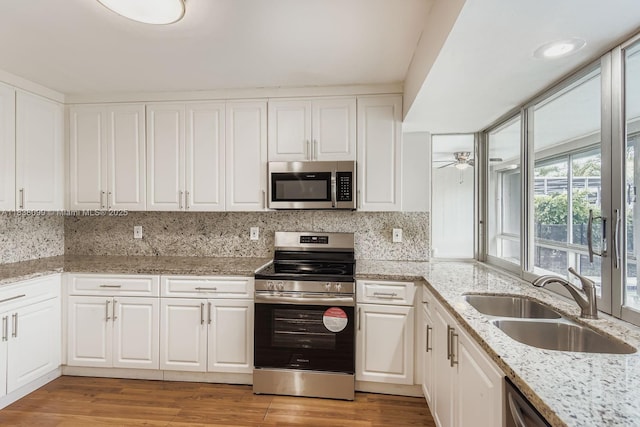 7904 Alhambra Blvd, Miramar, FL 33023 - kitchen featuring stainless steel appliances, white cabinets, light wood-style floors, tasteful backsplash, and light stone counters