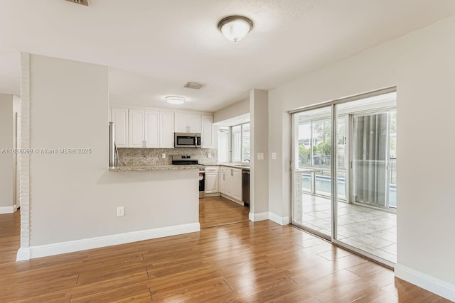 7904 Alhambra Blvd, Miramar, FL 33023 - kitchen with stainless steel appliances, white cabinets, light wood finished floors, a peninsula, and tasteful backsplash