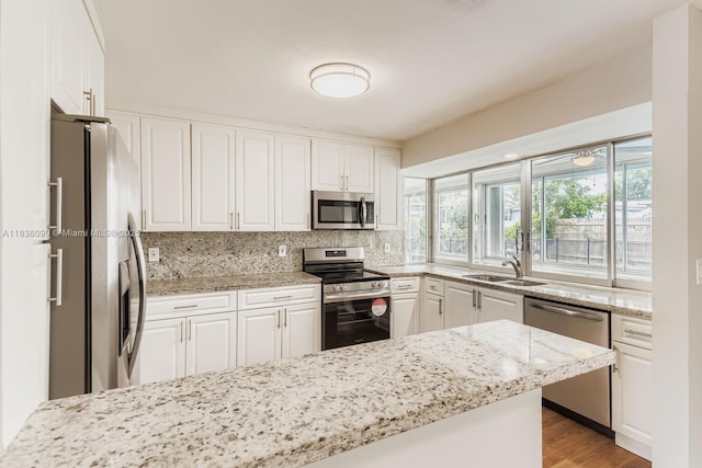 7904 Alhambra Blvd, Miramar, FL 33023 - kitchen featuring appliances with stainless steel finishes, white cabinetry, backsplash, light stone counters, and light wood-style flooring