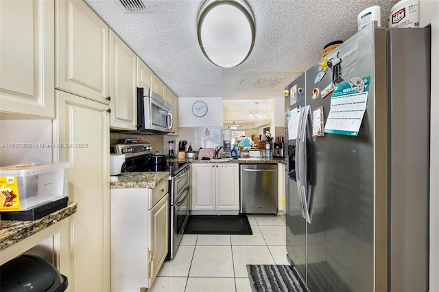 1178 NW 123rd Pl Unit 1210, Miami, FL 33182 - kitchen featuring appliances with stainless steel finishes, light tile patterned floors, cream cabinets, stone countertops, and a textured ceiling