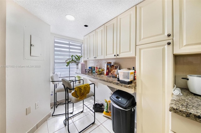 1178 NW 123rd Pl Unit 1210, Miami, FL 33182 - kitchen with a textured ceiling, cream cabinetry, stone counters, light tile patterned floors, and electric panel