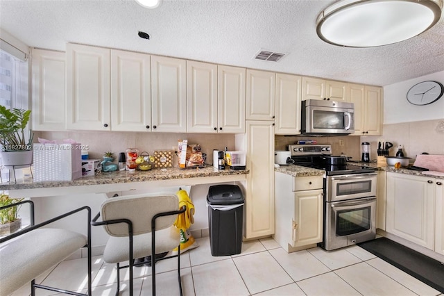 1178 NW 123rd Pl Unit 1210, Miami, FL 33182 - kitchen featuring stainless steel appliances, light stone counters, a textured ceiling, and light tile patterned flooring