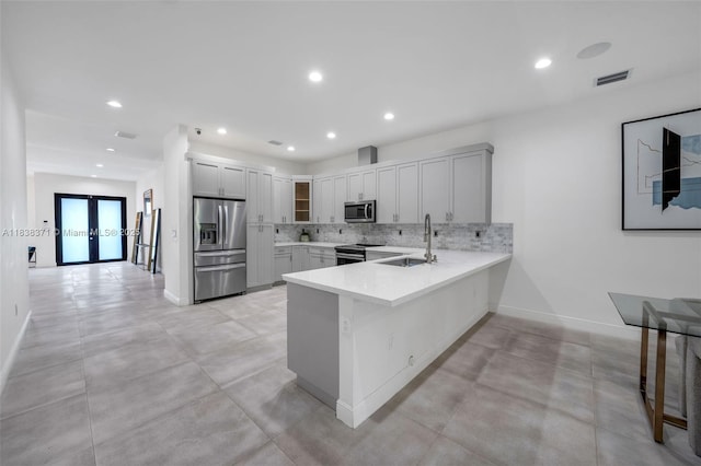 14832 SW 39th Ter, Miami, FL 33185 - kitchen featuring stainless steel appliances, a peninsula, light countertops, french doors, and decorative backsplash