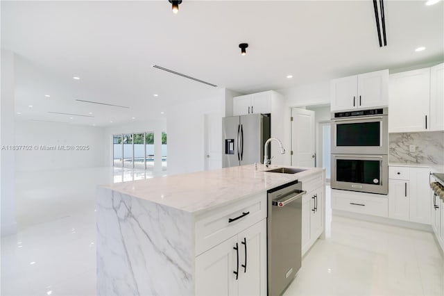 9800 SW 159th St, Miami, FL 33157 - kitchen featuring stainless steel appliances, white cabinets, light stone counters, a kitchen island with sink, and recessed lighting