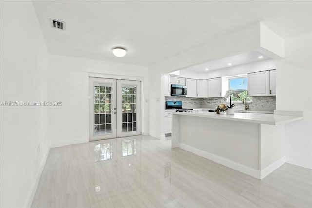 6424 Pierce St, Hollywood, FL 33024 - kitchen with stainless steel microwave, stove, french doors, decorative backsplash, and light countertops