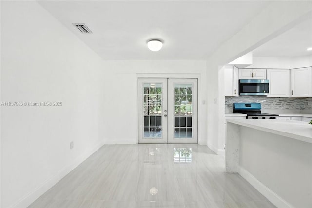 6424 Pierce St, Hollywood, FL 33024 - kitchen featuring stainless steel appliances, french doors, light countertops, white cabinetry, and backsplash