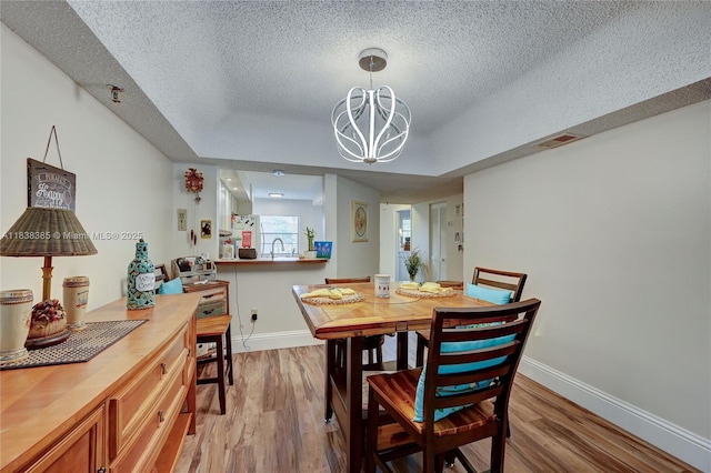 23344 Carolwood Ln Unit 303, Boca Raton, FL 33428 - dining space featuring a textured ceiling, wood finished floors, a chandelier, and a raised ceiling
