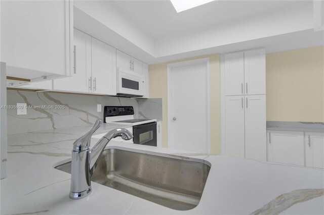 1900 N 31st Ave, Hollywood, FL 33021 - kitchen with white microwave, electric range oven, white cabinetry, and light stone counters