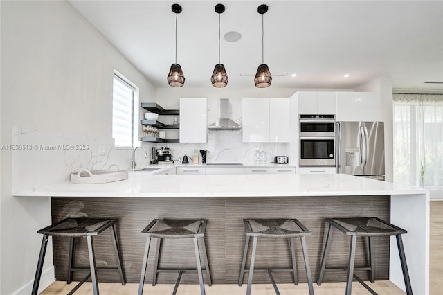 1617 NE 11th St Unit 1, Fort Lauderdale, FL 33304 - kitchen with stainless steel appliances, wall chimney range hood, open shelves, a peninsula, and tasteful backsplash