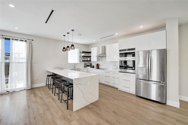 1617 NE 11th St Unit 1, Fort Lauderdale, FL 33304 - kitchen with appliances with stainless steel finishes, wall chimney range hood, modern cabinets, a kitchen breakfast bar, and a peninsula