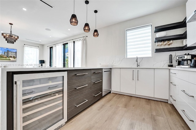 1617 NE 11th St Unit 1, Fort Lauderdale, FL 33304 - kitchen with beverage cooler, white cabinetry, light countertops, light wood finished floors, and pendant lighting