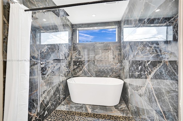 1617 NE 11th St Unit 1, Fort Lauderdale, FL 33304 - full bathroom featuring marble tiled floors, plenty of natural light, a freestanding tub, tiled shower, and tile walls