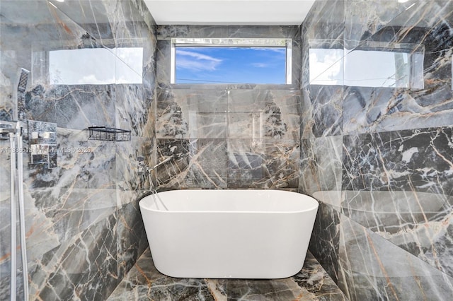 1617 NE 11th St Unit 1, Fort Lauderdale, FL 33304 - bathroom with tile walls, marble tiled flooring, and a freestanding bath