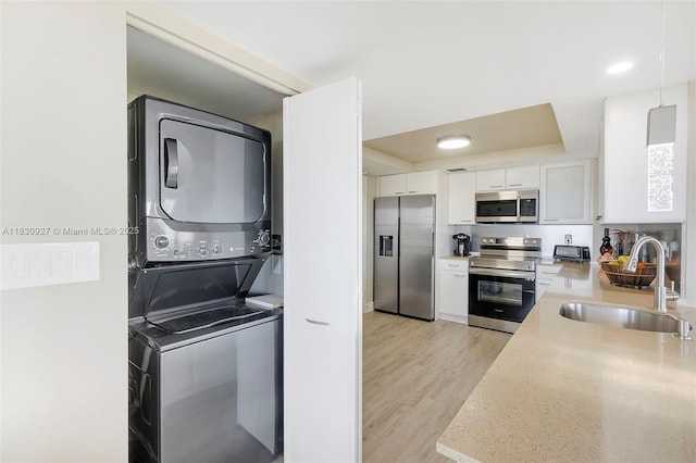 3200 N Port Royale Dr N Unit 1612, Fort Lauderdale, FL 33308 - kitchen featuring appliances with stainless steel finishes, stacked washer / drying machine, a raised ceiling, white cabinets, and light countertops