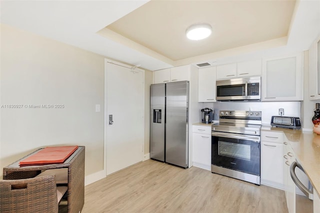 3200 N Port Royale Dr N Unit 1612, Fort Lauderdale, FL 33308 - kitchen with appliances with stainless steel finishes, a raised ceiling, light countertops, and light wood-style flooring