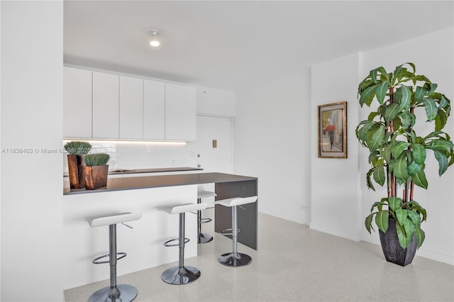 3 Island Ave Unit 12E, Miami Beach, FL 33139 - kitchen with a kitchen bar, white cabinets, a peninsula, modern cabinets, and backsplash