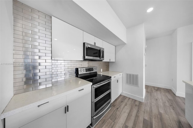 13155 Ixora Ct Unit 1105, North Miami, FL 33181 - kitchen with appliances with stainless steel finishes, light wood-type flooring, white cabinets, backsplash, and recessed lighting
