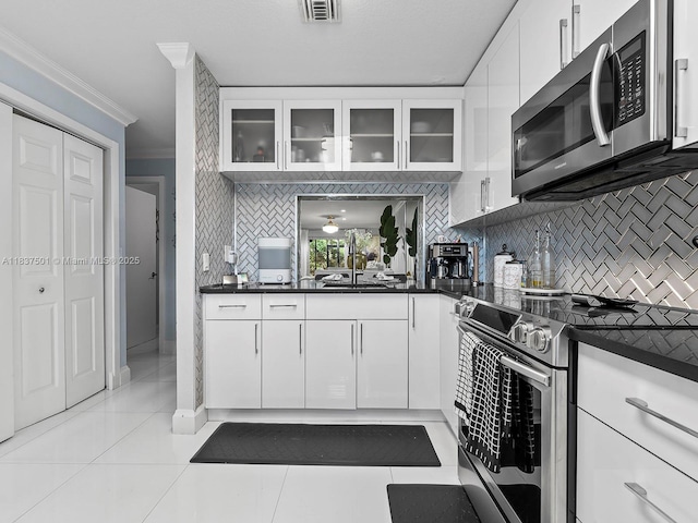 10942 W Sample Rd Unit E1, Coral Springs, FL 33065 - kitchen featuring stainless steel appliances, ornamental molding, dark countertops, decorative backsplash, and glass insert cabinets